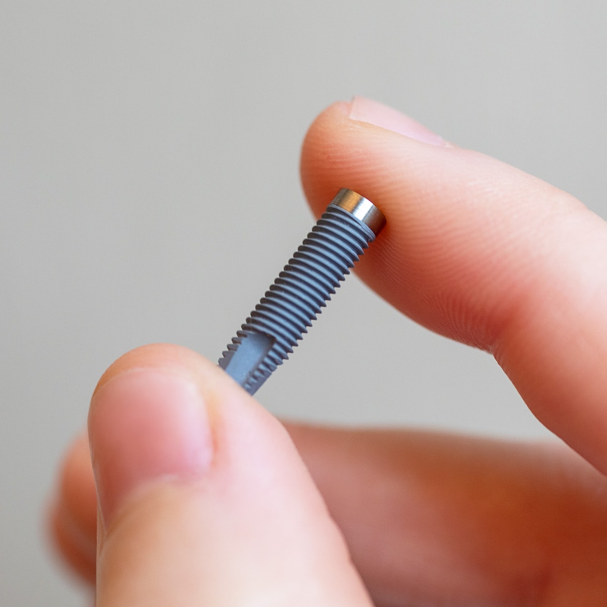 Dental Implant example 1 Close-up of titanium Dental Implant within thumb and forefinger